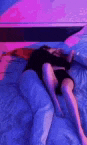 a woman in a black dress is laying on a bed with purple lights .