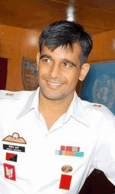 a man in a military uniform is smiling and wearing medals on his shoulder .