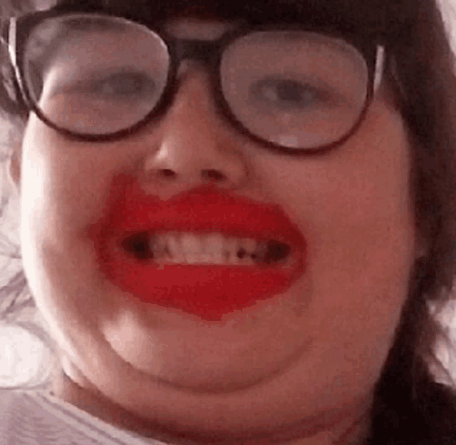 a woman wearing glasses and red lipstick smiles