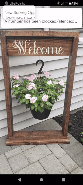 a phone screen displays a welcome sign with flowers in it