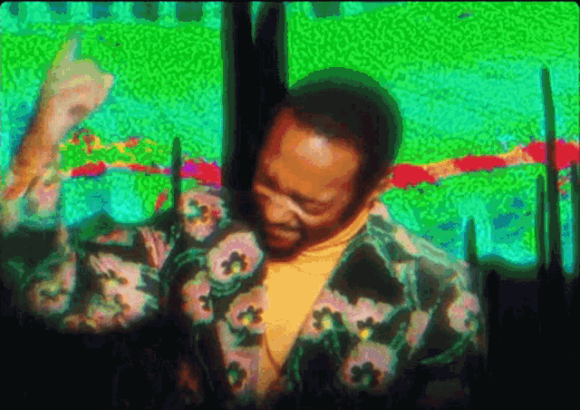 a man in a floral jacket is dancing in front of a green and red background .