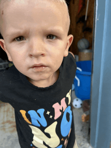 a little boy wearing a black shirt that says " no " on it