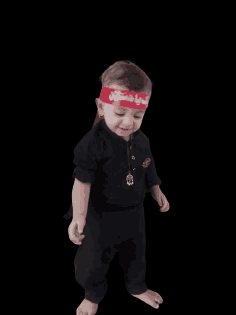 a little boy wearing a red headband with arabic writing