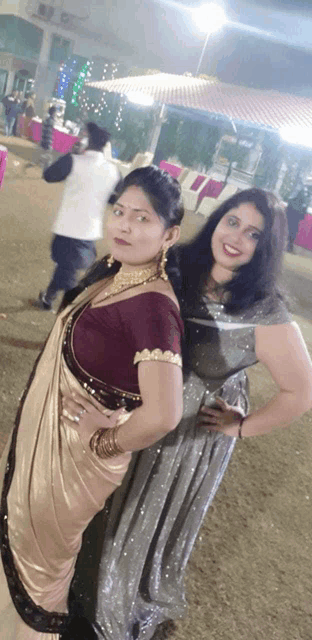 two women posing for a picture with one wearing a saree