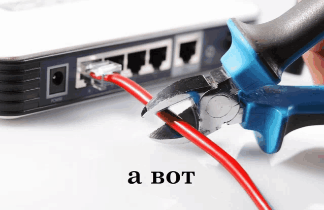 a person is cutting a red wire with a pair of pliers in front of a router