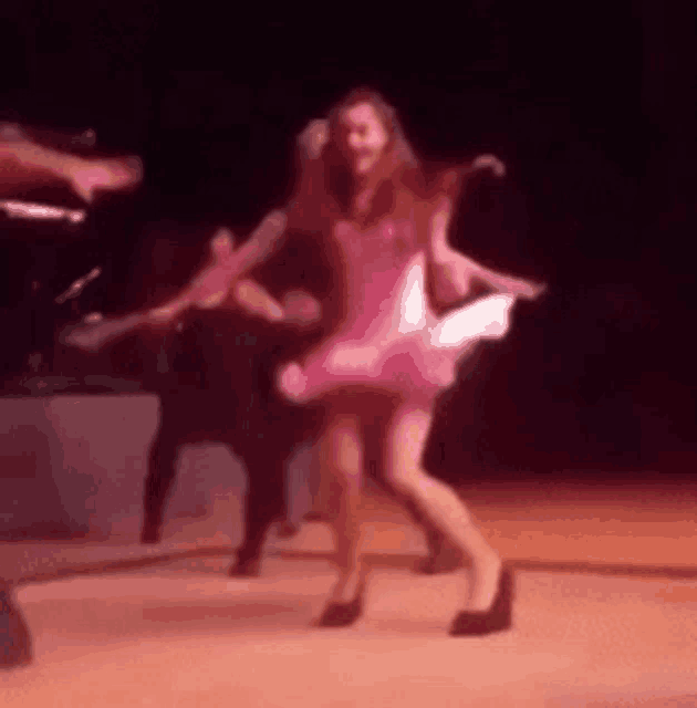 a woman in a pink dress is dancing on a stage