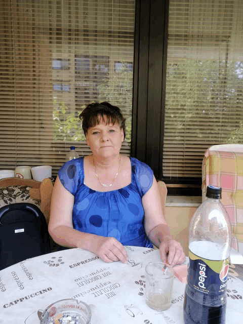 a woman sitting at a table with a bottle of pepsi