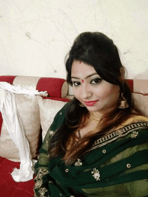 a woman sitting on a couch wearing a green sari