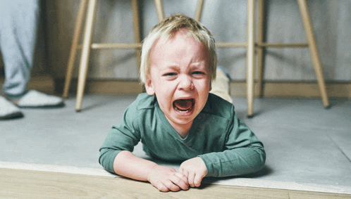 a little boy is crying on the floor with his mouth open