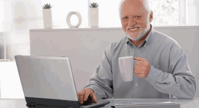 an elderly man is sitting at a desk with a laptop and a cup of coffee