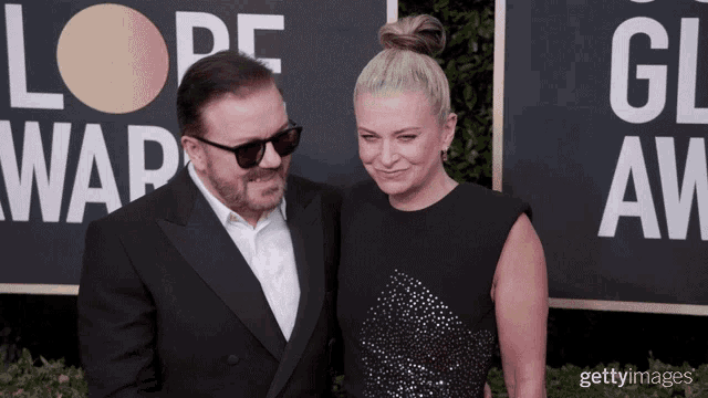 a man and a woman are posing for a picture on a red carpet in front of a sign that says globe awards