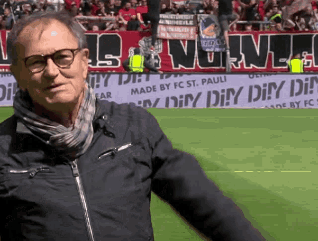 a man stands on a soccer field in front of a banner that says ' made by fc st. pauli '