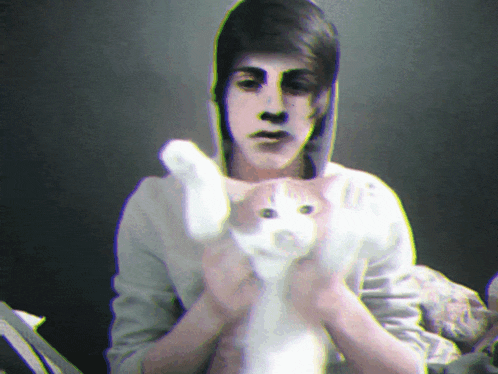 a man in a hoodie holds a cat in his arms