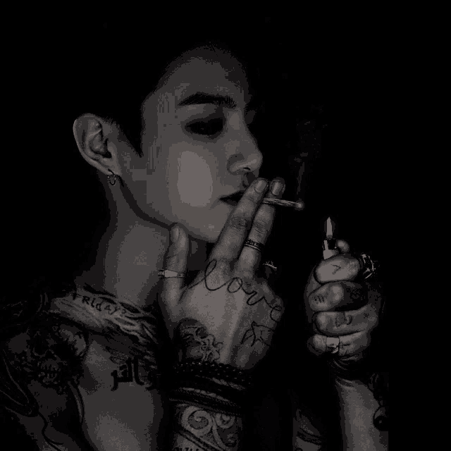 a tattooed man is smoking a cigarette with the word love on his hand