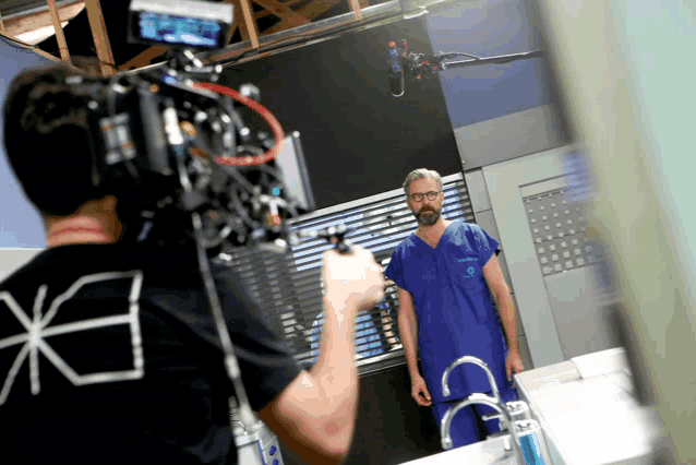 a man in a scrub is being filmed by a camera