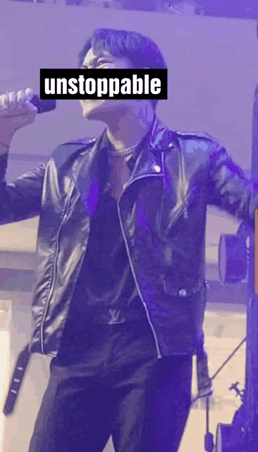 a man in a black leather jacket singing into a microphone with the word unstoppable visible