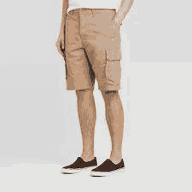 a man is wearing a pair of khaki cargo shorts and black sneakers .