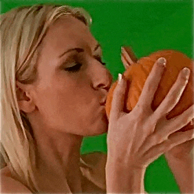 a woman is kissing a pumpkin against a green background .