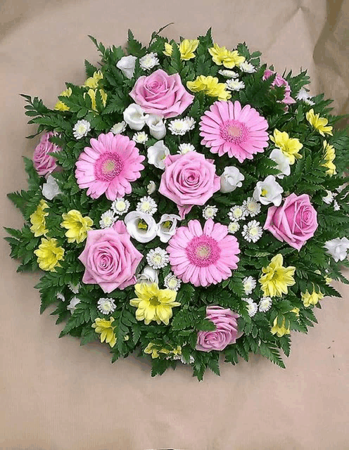 a bouquet of pink and yellow flowers on a brown surface