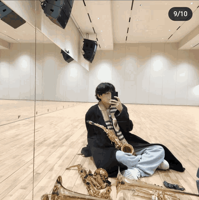 a man sits on the floor playing a saxophone and taking a picture