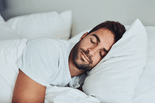 a man with a beard is sleeping on a bed with his eyes closed