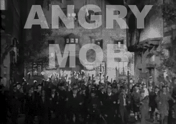 a black and white photo of a crowd of people walking down a street with the words angry mob written above them