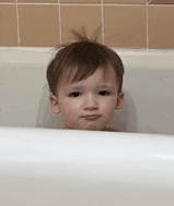 a young boy is sitting in a bathtub and looking out of it .