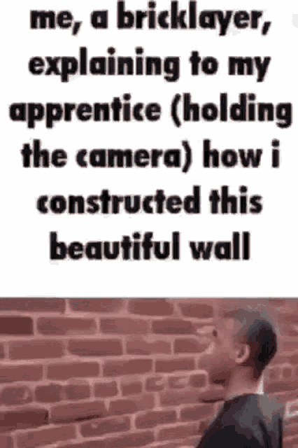 a man is standing in front of a brick wall with a bricklayer explaining to his apprentice holding the camera .