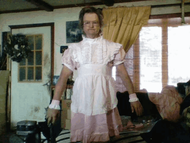 a man in a pink dress and apron is standing in a room