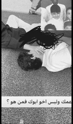 a black and white photo of a person laying on the ground with arabic writing