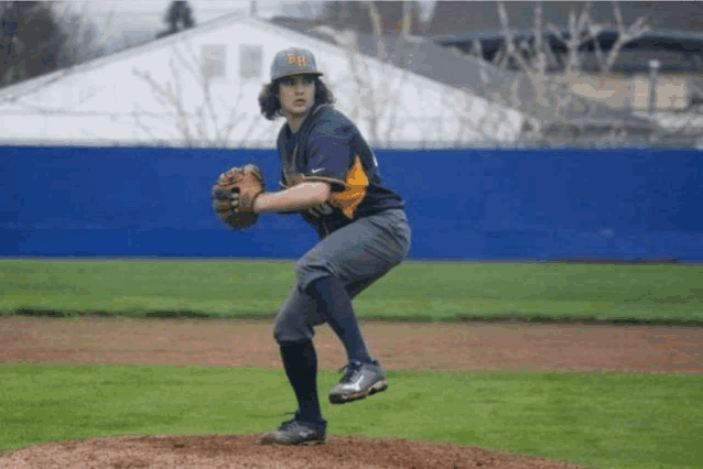 a baseball player wearing a bh hat is about to throw a pitch