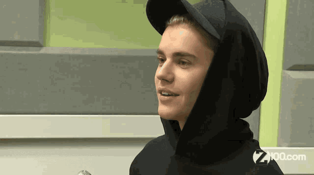 justin bieber is wearing a black hoodie and a hat