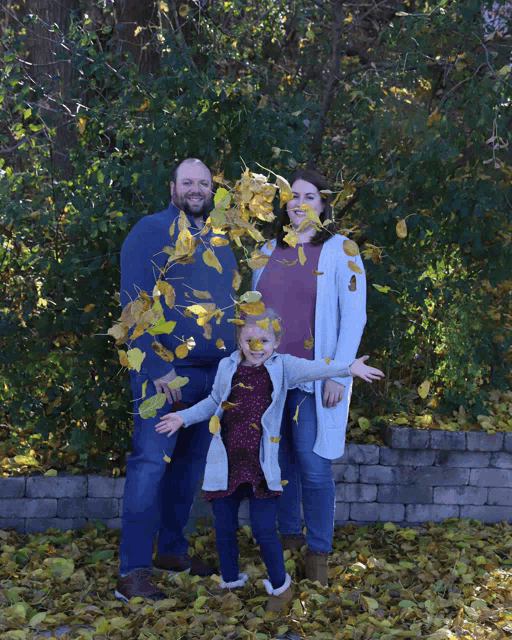 a family posing for a picture with leaves being thrown in the air