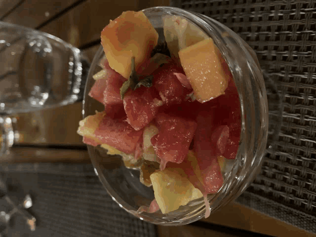 a glass bowl filled with sliced fruit including grapefruit and pineapple