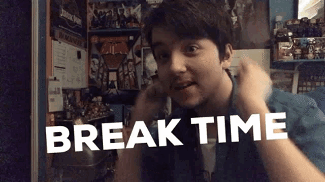 a young man is making a funny face in front of a wall with the words break time on it .