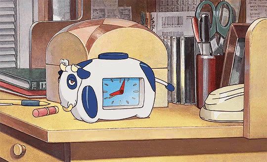 a cow shaped alarm clock sits on a desk next to a pair of scissors