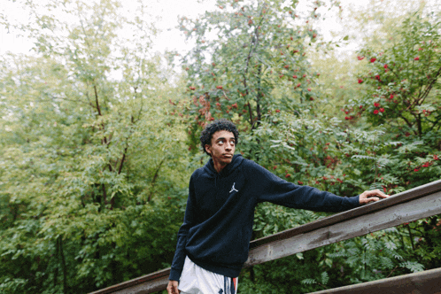 a man leaning on a railing with a hoodie that says air jordan