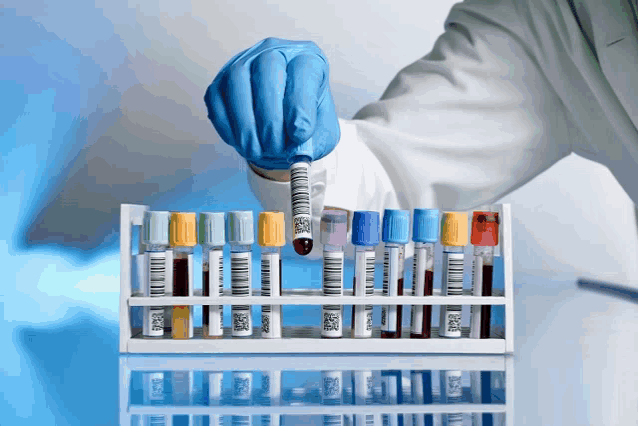 a scientist holds a test tube with a barcode on it over a rack of test tubes