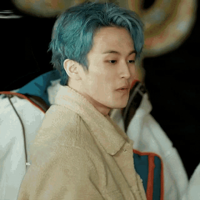 a man with blue hair is wearing a jacket