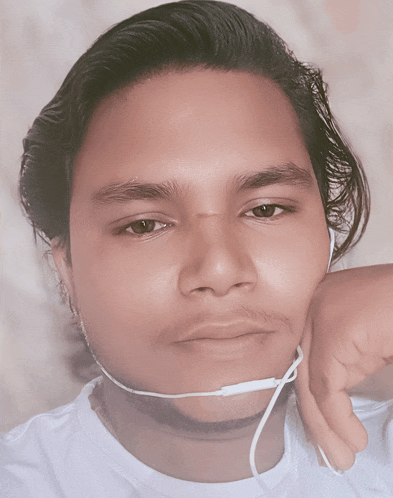 a young man wearing a white shirt and ear buds looks at the camera