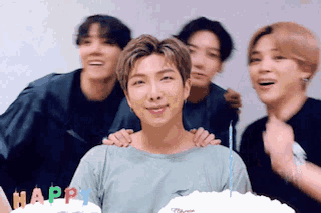 a group of young men are posing for a picture in front of a cake that says happy on it .