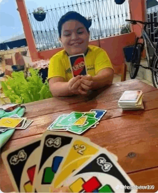 a boy is playing a game of uno with a yellow shirt on