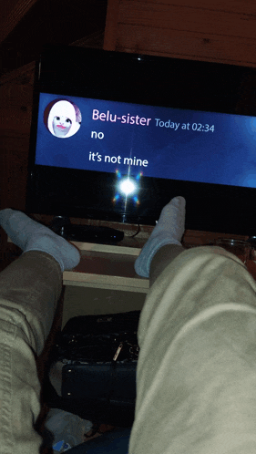 a person sitting in front of a television with a message from beli-sister