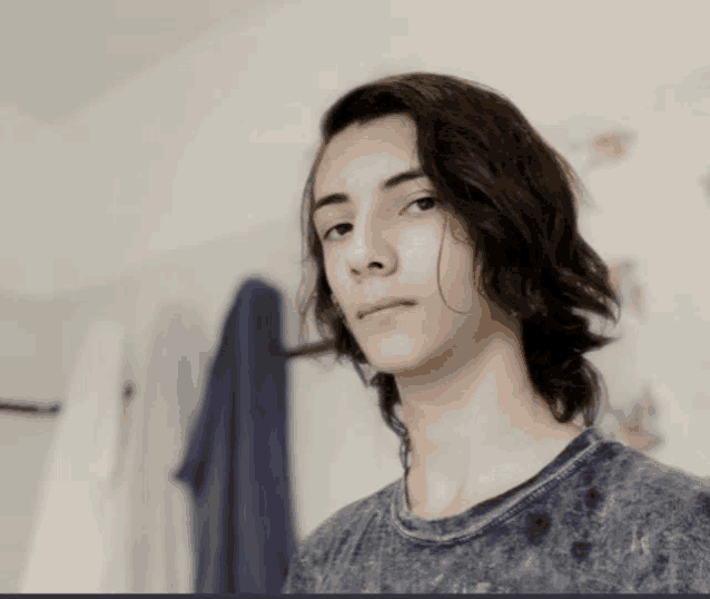 a young man with long hair wearing a grey shirt