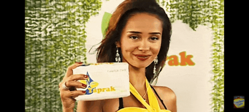 a woman in a yellow top is holding up a box that says ' aprak ' on it