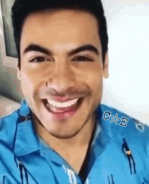 a close up of a man 's face with a blue shirt on smiling