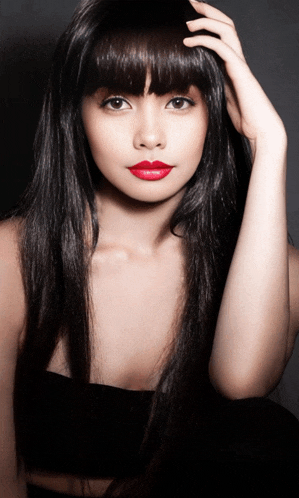 a woman with long black hair and red lipstick looks at the camera