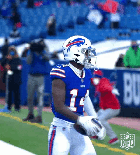 a football player in a buffalo bills uniform is holding a football .