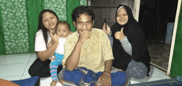 a group of people are posing for a picture and one woman is giving a thumbs up sign