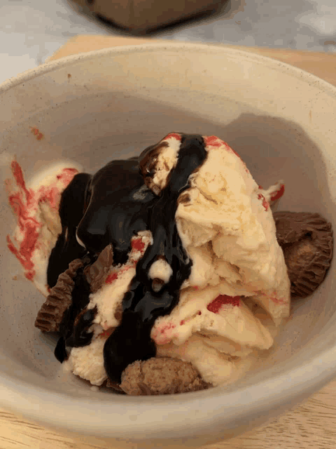 a bowl of ice cream with chocolate sauce and peanut butter cups in it